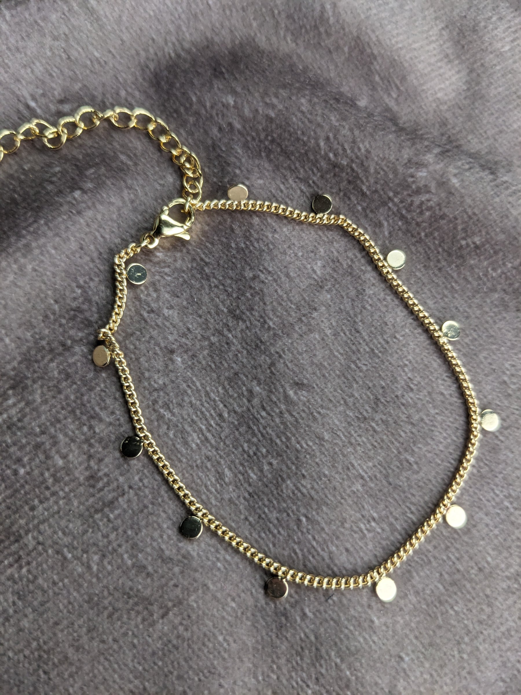 Goldenes gliederfußband mit vielen kleinen kreisplättchen