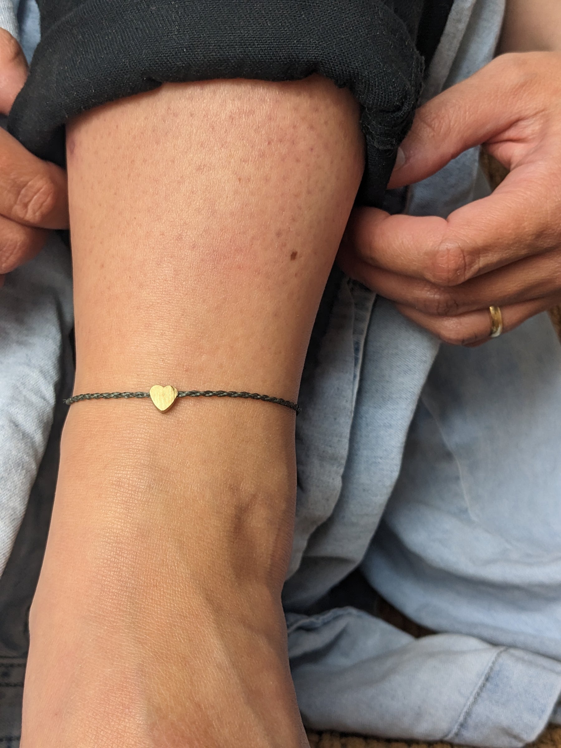 einfaches freundschaftsband mit goldenem Herz oder Sonne . minimalistisches fußband in naturtönen