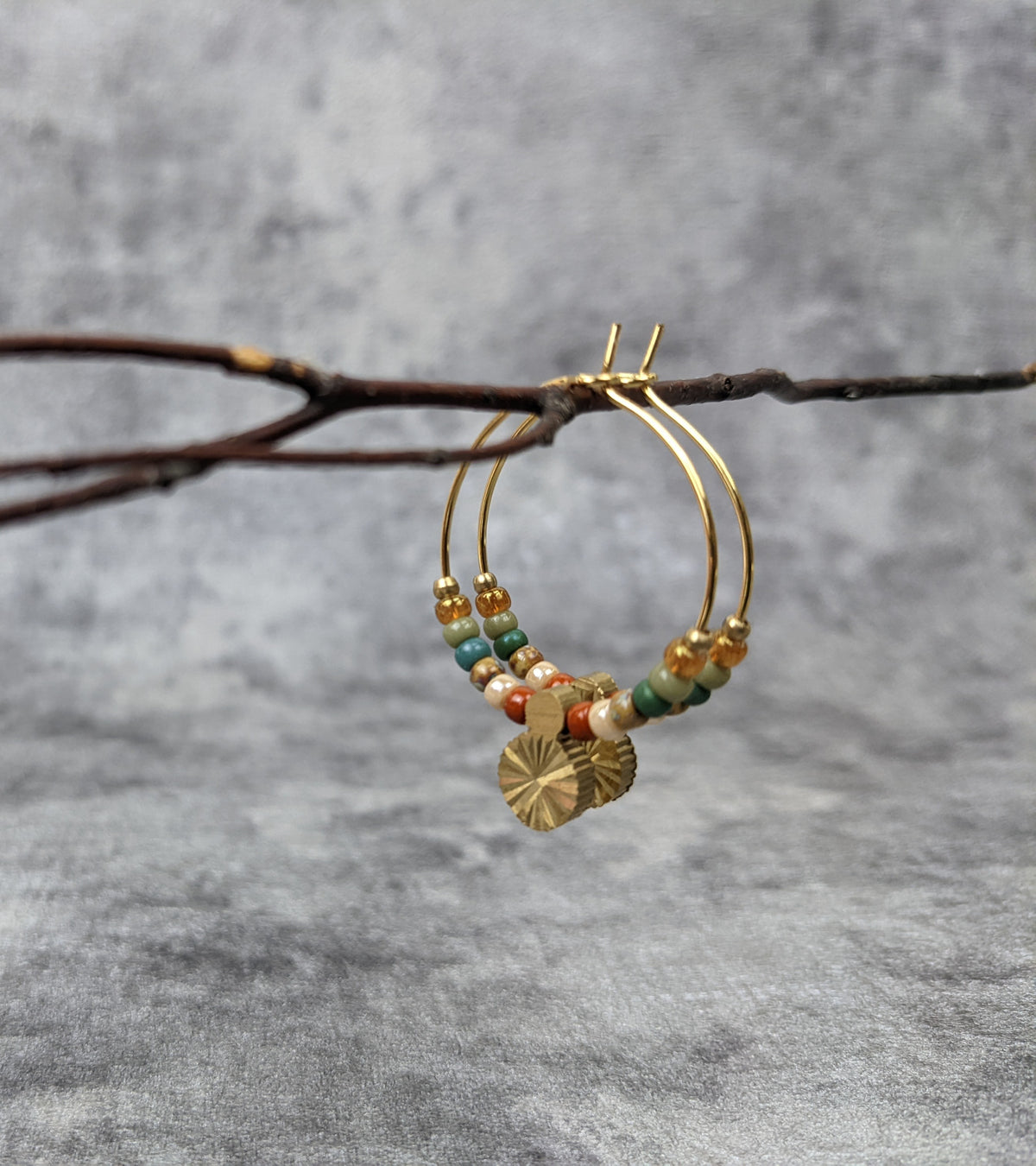 bunte glasperlenohrringe mit goldener messingsonne im ethnolook . goldene kreolen mit sonne