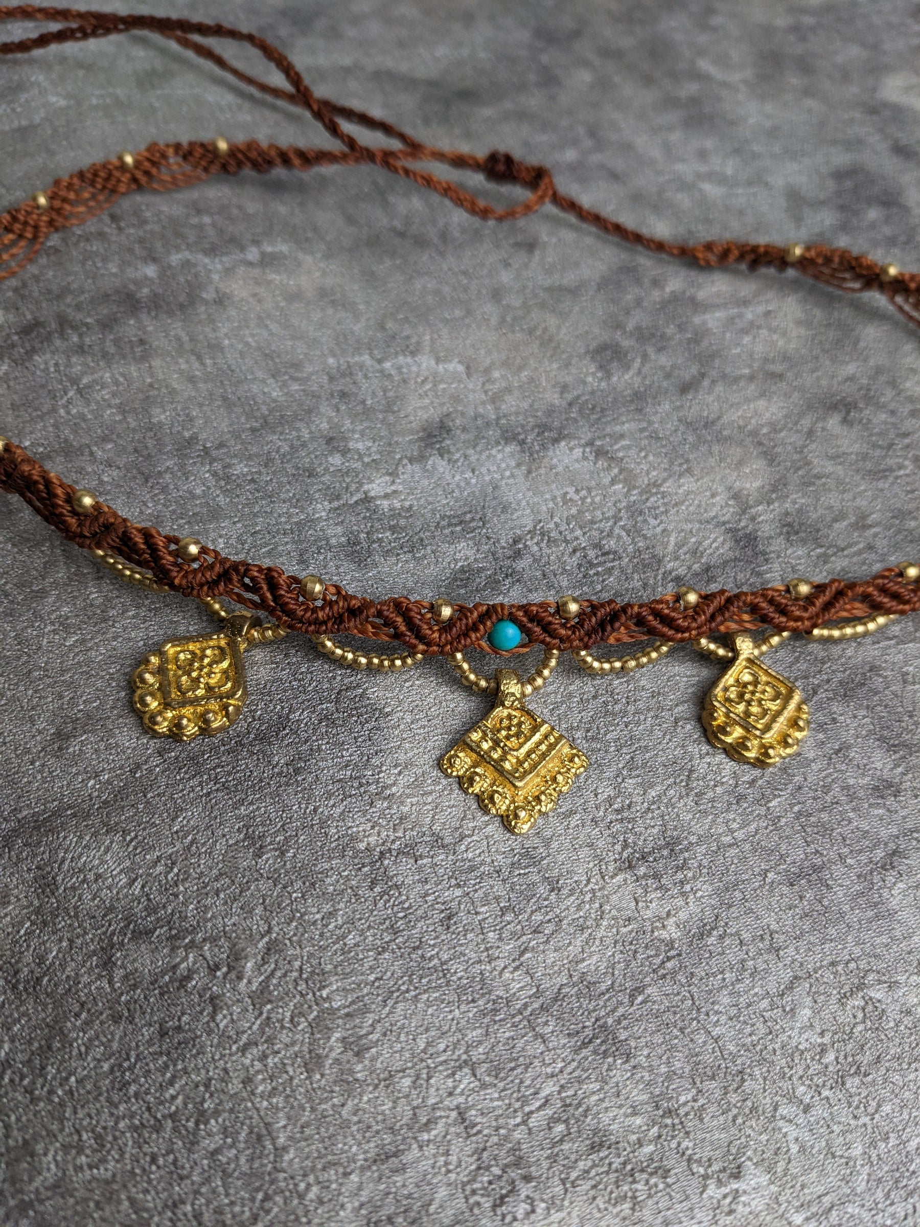 indischer kopschmuck mit hängenden goldenen ornamenten an braunem nylonband