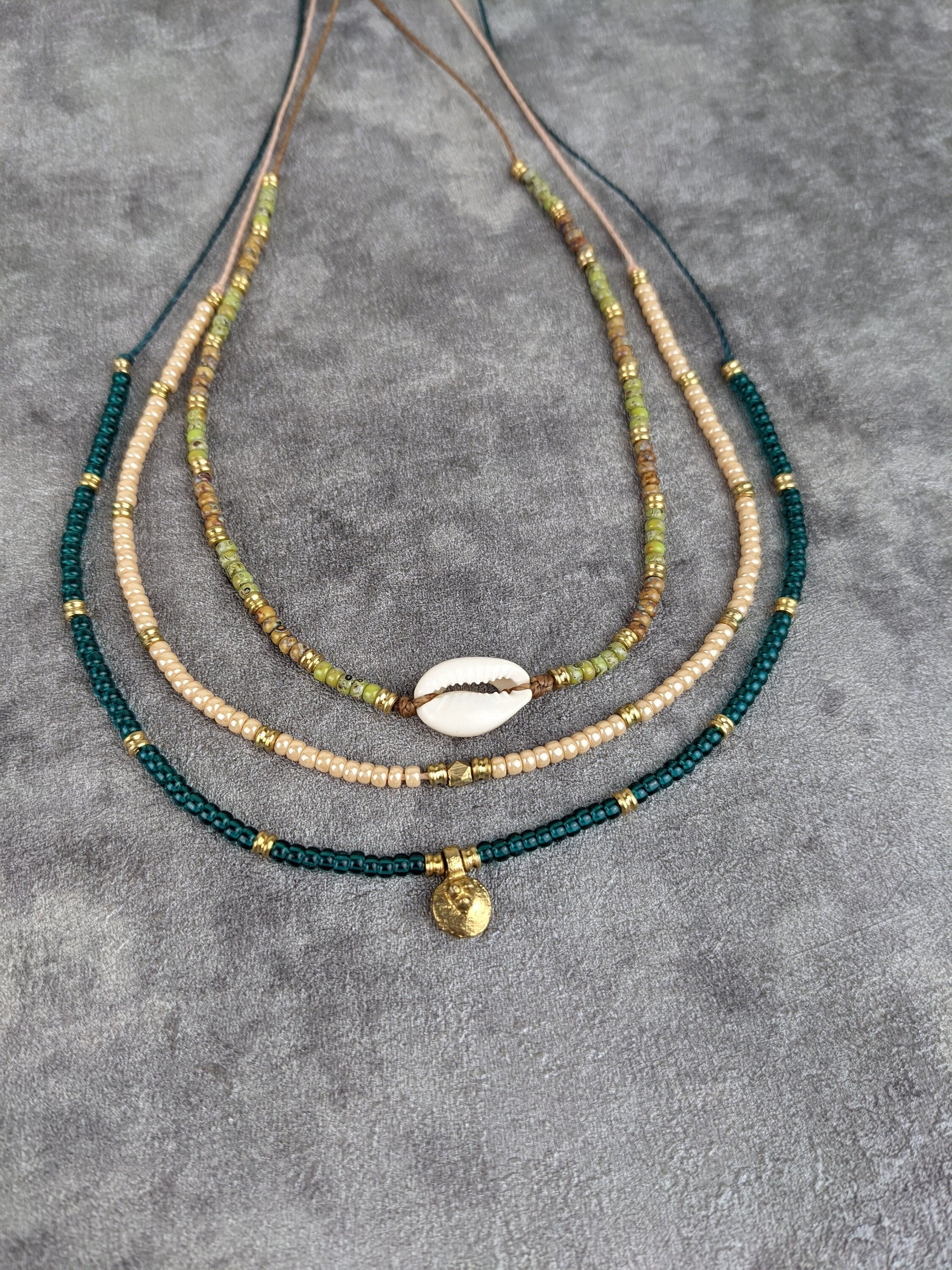 glasperlenkette mit kauri muschel ung grünen und braunen glasperlen sowie goldenen messingperlen