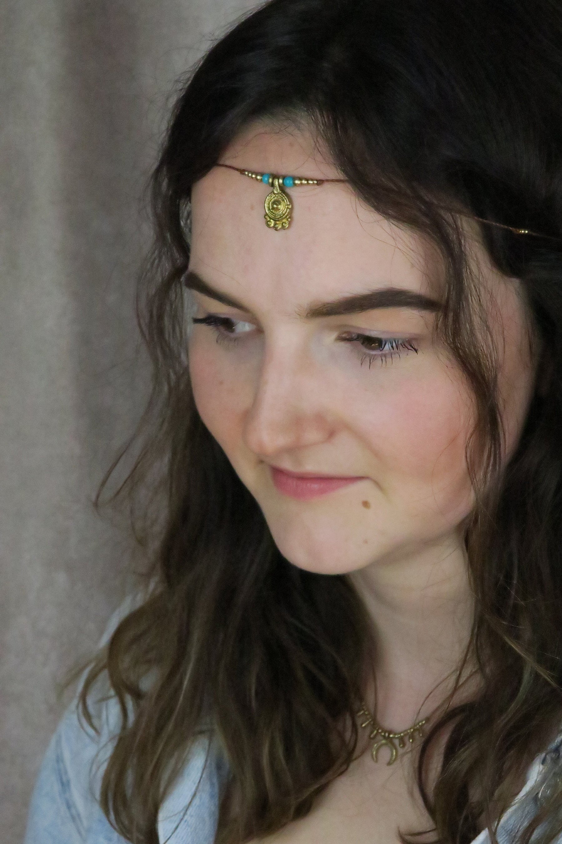 minimalistische stirnkette mit türkisen steinperlen und goldenem ornament im boho stil